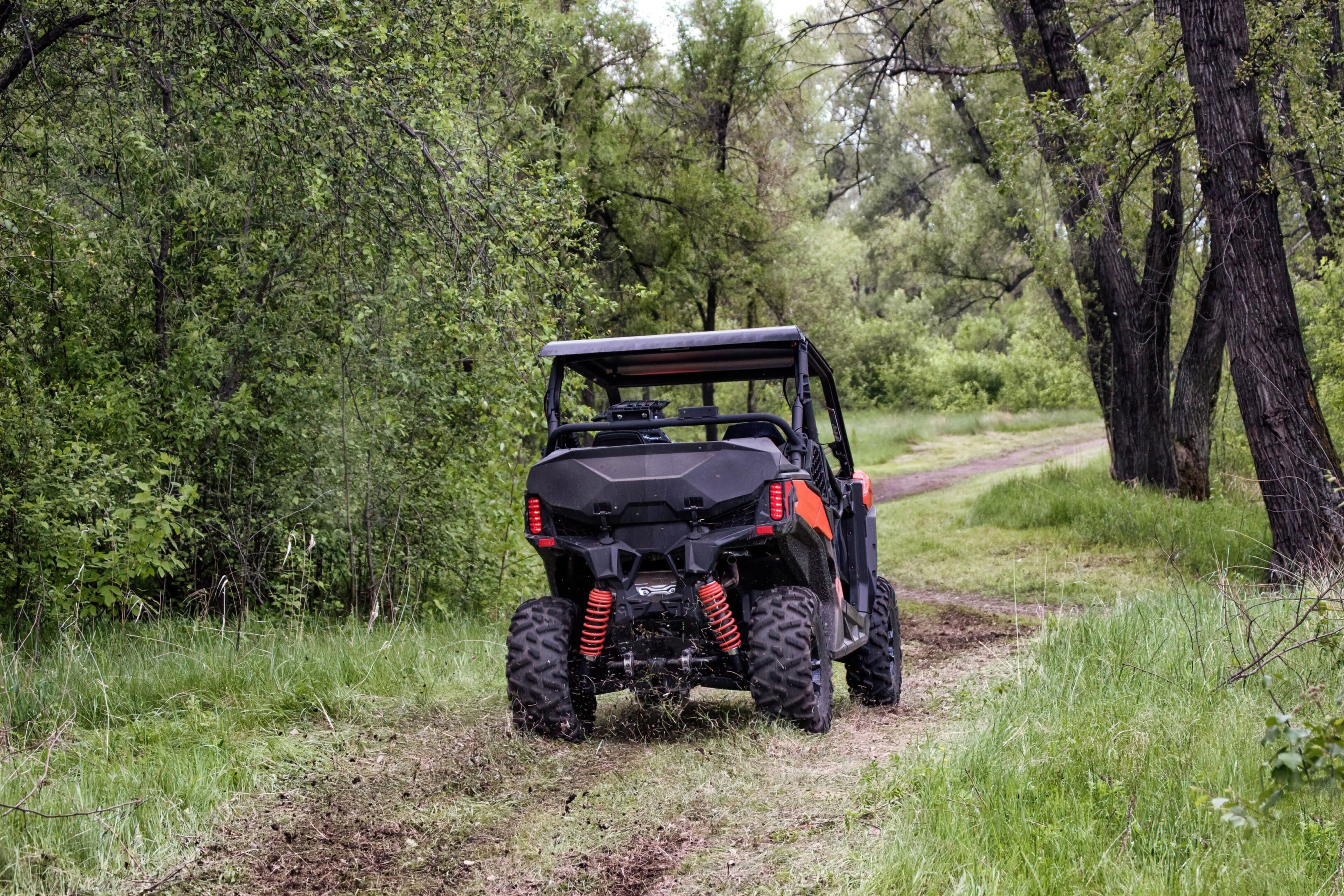 A black and red vehicle is parked on the side of a dirt road.