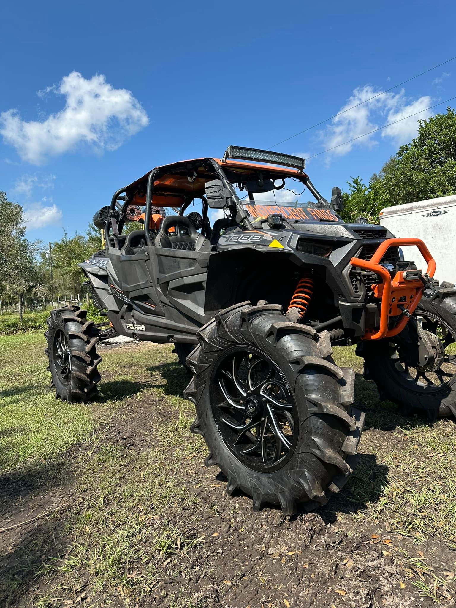A black and orange four wheeler parked in the grass.