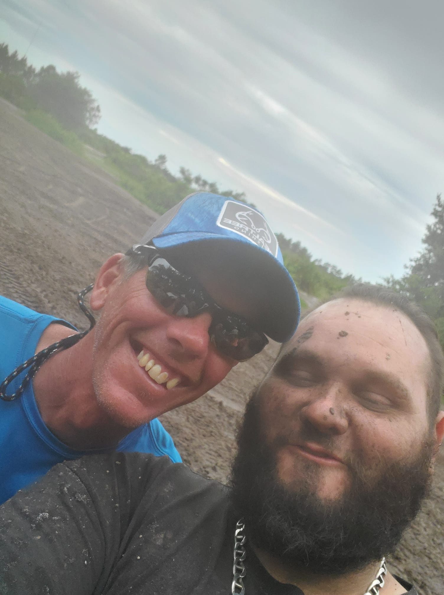 Two men smiling for a picture in the dirt.