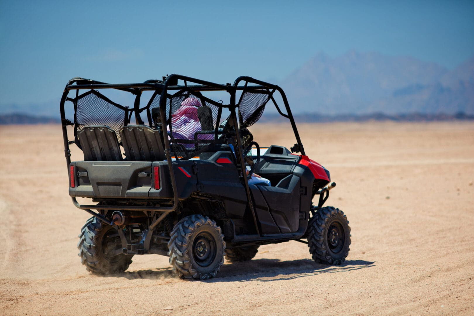 All-terrain vehicle driving across sandy desert